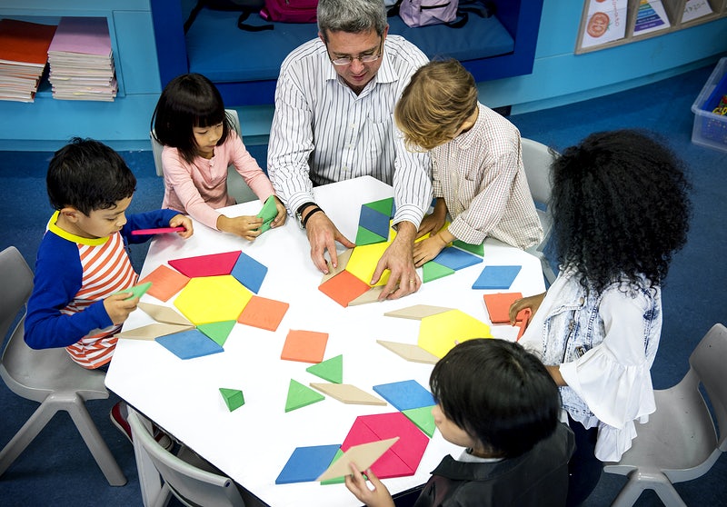 crianças fazendo atividade junto com o professor ilustrando a execução do planejamento estratégico escolar. 