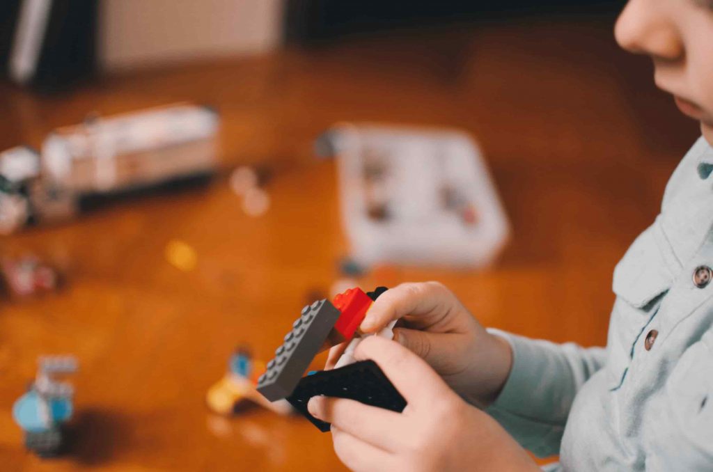 Criança segura brinquedo de encaixe, exercitando a matemática na Educação Infantil.