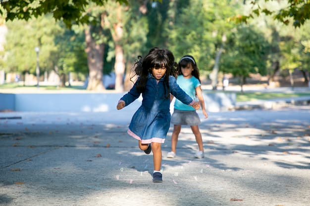 Duas meninas brincando de amerelinha em uma praça, uma das atividades de coordenação motora ampla sugeridas.