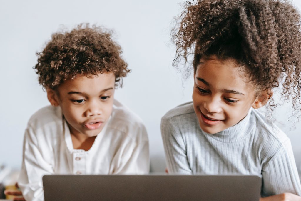 Uma menina e um menino interagindo com material didático online.