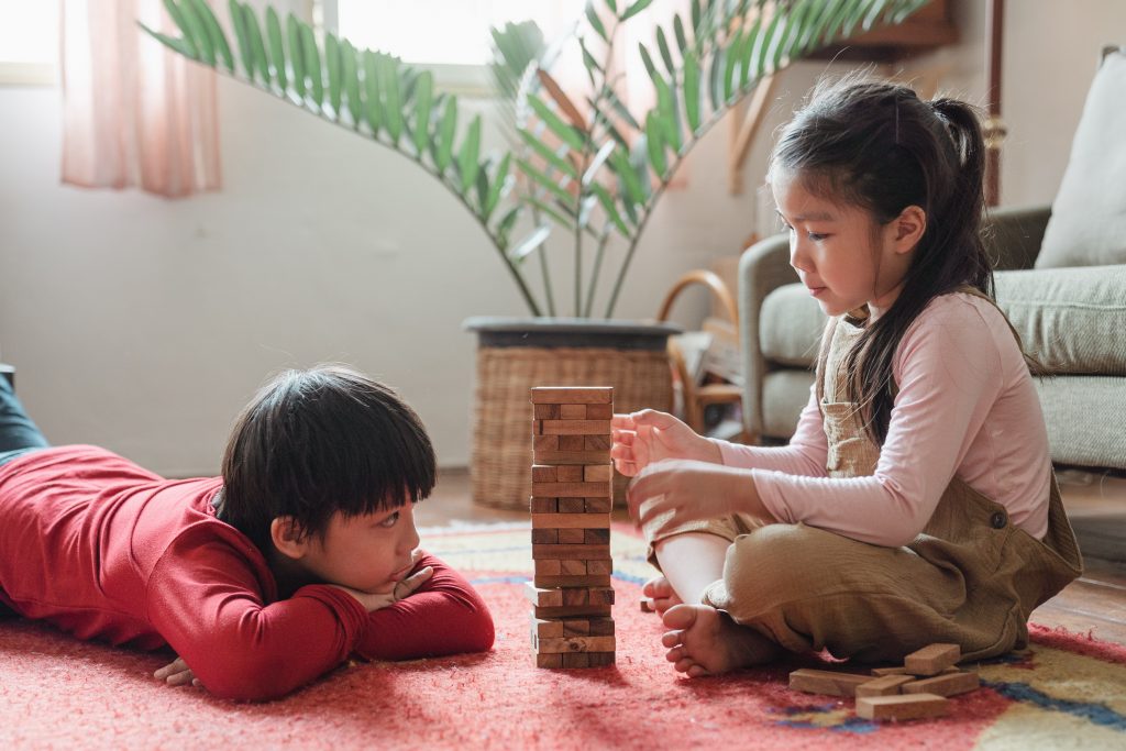 Uma menina e um menino brindo o jogo da torre demonstrando opções para a matemática lúdica.