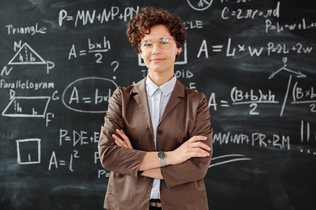 Aluna do Ensino Médio em frente a um quadro com fórmulas matemáticas demonstrando que o conteúdo fica mais divertido com a matemática lúdica.