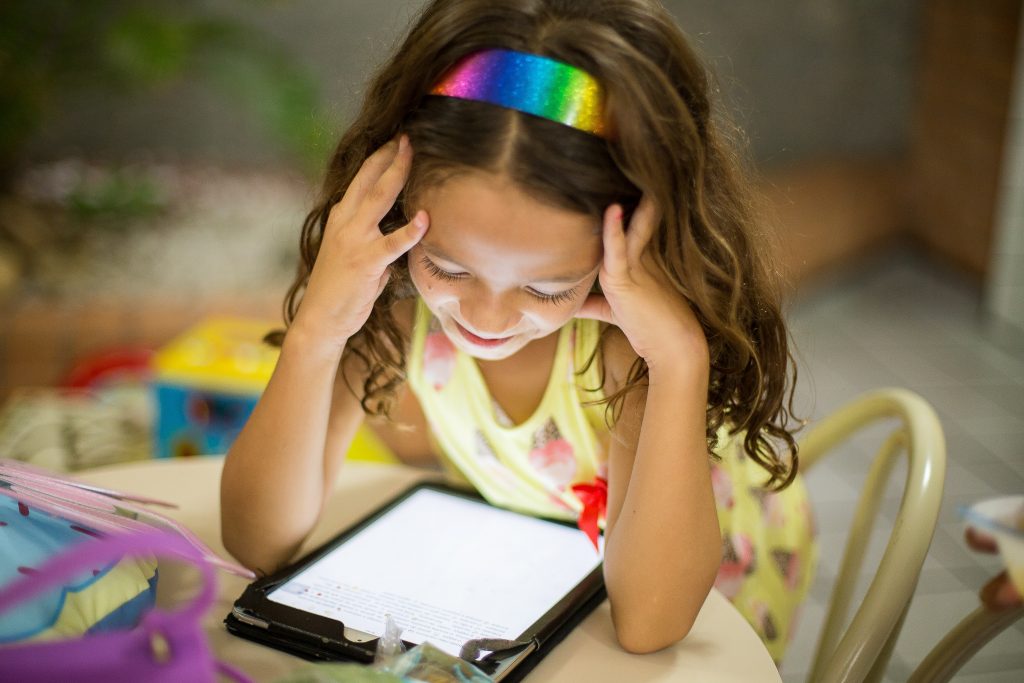 Uma menina estudando em aplicativos para alfabetização em um tablet.